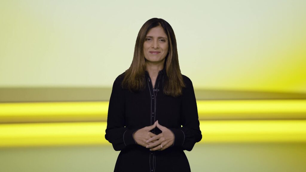 A woman standing in front of a yellow and white background