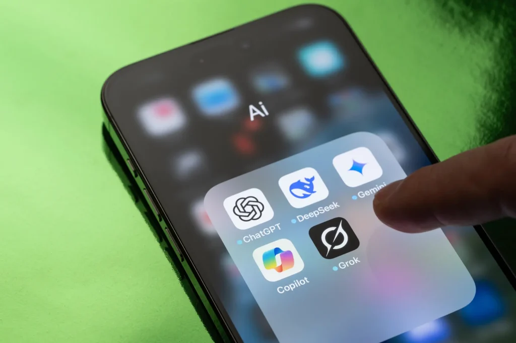 Smartphone screen showing AI apps including ChatGPT, DeepSeek for deep research, Gemini, Copilot, and Grok.