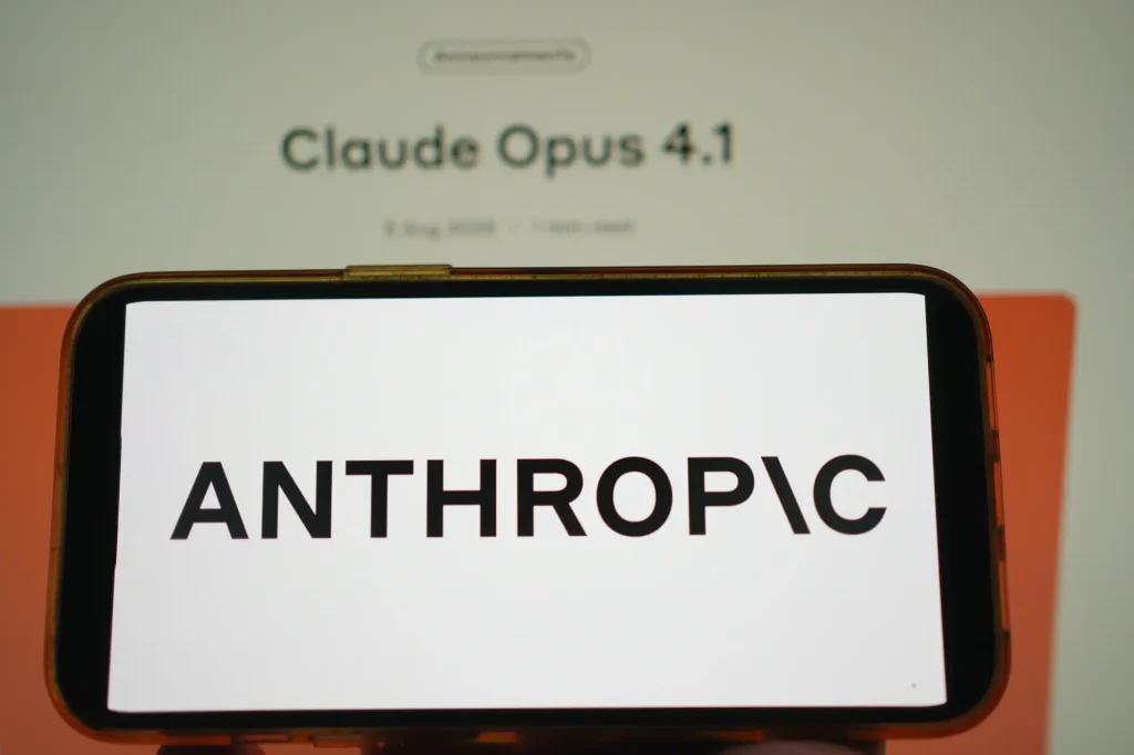 Opus 4 announcement with Anthropic logo in foreground and “Claude Opus 4.1” headline visible on the screen behind